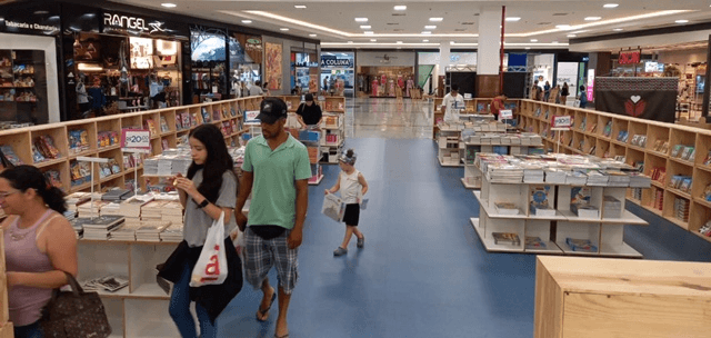 Registro de uma feira de livros dentro de um shopping mall, com adultos e crianças circulando pela praça.